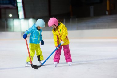 Çocuk kapalı pistinde buz hokeyi oyun. Çocuklar için sağlıklı kış sporları. Erkek ve kız hokey topu isabet sopa ile. Çocuk buz pateni. Spor okuldan sonra eğitim üzerinde küçük bir çocuk. Kar ve buz eğlenceli.