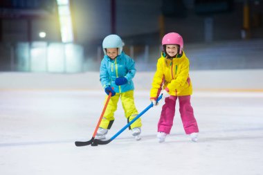 Çocuk kapalı pistinde buz hokeyi oyun. Çocuklar için sağlıklı kış sporları. Erkek ve kız hokey topu isabet sopa ile. Çocuk buz pateni. Spor okuldan sonra eğitim üzerinde küçük bir çocuk. Kar ve buz eğlenceli.