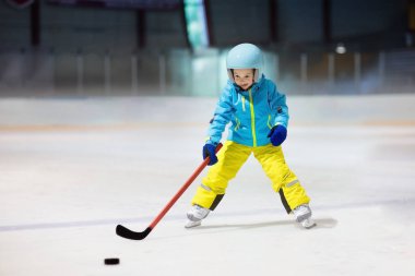 Çocuk kapalı pistinde buz hokeyi oyun. Çocuklar için sağlıklı kış sporları. Hokey sopası puck isabet çocuk. Çocuk buz pateni. Spor okuldan sonra eğitim üzerinde küçük bir çocuk. Kar ve buz eğlenceli.