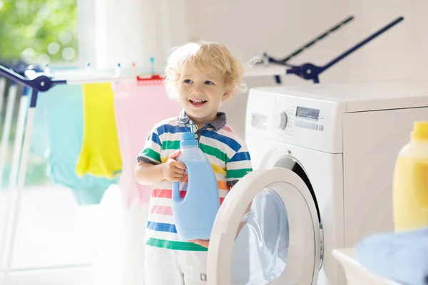 儿童在洗衣房内设有洗衣机或滚筒烘干机 帮助家庭琐事的孩子 现代家庭设备和洗涤洗涤剂在白色阳光的家 烘干机架清洗洗衣服 — 图库照片