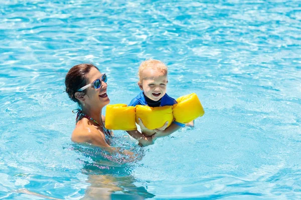 妈妈和宝宝在热带度假胜地的室外游泳池里 孩子在学游泳 妈妈和孩子在水里玩耍 家庭暑假在异国情调的目的地 积极健康的儿童体育运动 — 图库照片
