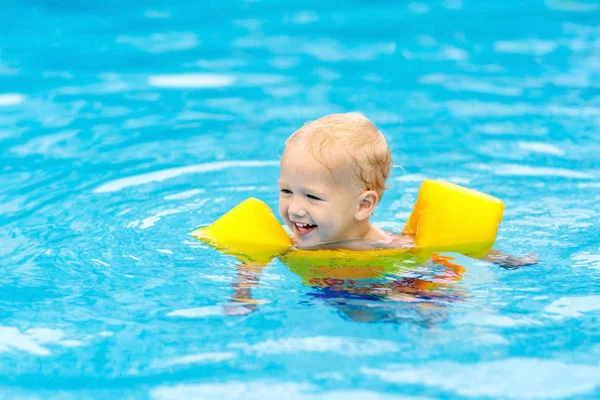スイミング プールで膨脹可能なアームバンドと赤ちゃん トロピカル リゾートの屋外プールで泳ぐことを学ぶ少年 子供たちと一緒に泳ぐ 子供のための健康的なスポーツ活動 夏休み エイズを泳ぐ — ストック写真