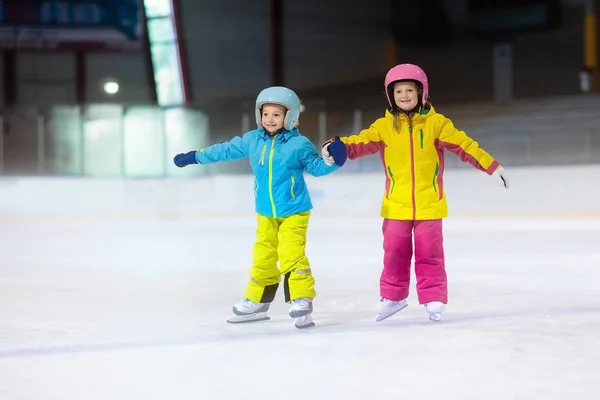 Children skating on indoor ice rink. Kids and family healthy winter sport. Boy and girl with ice skates. Active after school sports training for young child. Snow fun activity by cold weather.