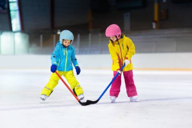 Çocuk kapalı pistinde buz hokeyi oyun. Çocuklar için sağlıklı kış sporları. Erkek ve kız hokey topu isabet sopa ile. Çocuk buz pateni. Spor okuldan sonra eğitim üzerinde küçük bir çocuk. Kar ve buz eğlenceli.