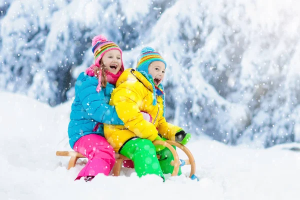 幼い女の子と男の子がそりに乗るのを楽しんでいます 子供のそり 幼児はそりに乗っている 子供たちは雪の中屋外で遊ぶ 冬のスノーパークで子供たちがそります 家族のための屋外の楽しみクリスマス休暇 — ストック写真