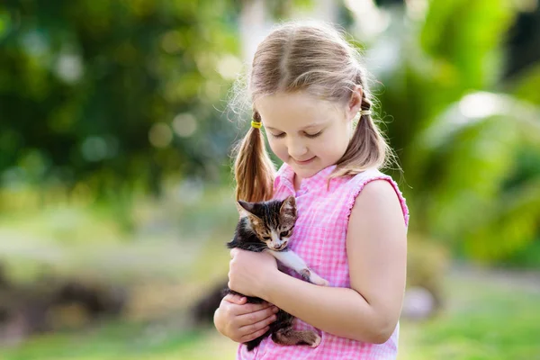 赤ちゃん猫を抱えている子供 子供とペット 夏の庭でかわいい子猫を抱いている女の子 子供連れの家庭内動物 ペット動物のいる子供たち — ストック写真