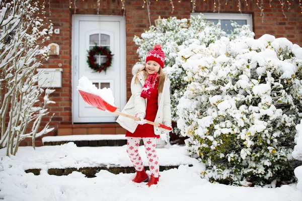 子供のシャベル雪 冬の吹雪の後に舗装されたクリアドライブウェイを持つ少女 クリスマスの吹雪の後 子供たちは家のドアへの明確なパス 雪の楽しみ 寒い霜の庭で遊ぶ子供たち — ストック写真