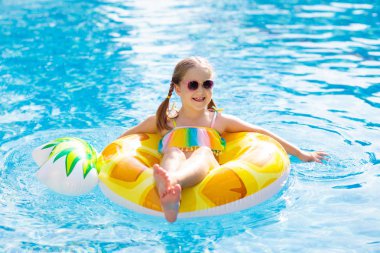 Şişme ananas yüzüklü çocuk yüzme havuzunda yüzüyor. Küçük kız yüzmeyi ve tropikal tatil köyü havuzuna dalmayı öğreniyor. Çocuklarla yüzmek. Çocuklar için sağlıklı bir spor. Su eğlencesi