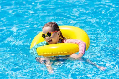 Çocuk yüzme havuzu güneş gözlüklü. Şişme yüzüğü küçük kız. Renkli float evlat. Çocuklar yüzmek ve tropikal resort açık yüzme havuzunda dalış öğrenin. Güneş koruma ve göz giymek. Su eğlenceli.