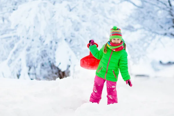 女の子はそりに乗るのを楽しんでいる 子供のそり 幼児はそりに乗っている 子供たちは雪の中屋外で遊ぶ 冬にはアルプスの山々で子供たちがそります 家族のための屋外の楽しみクリスマス休暇 — ストック写真