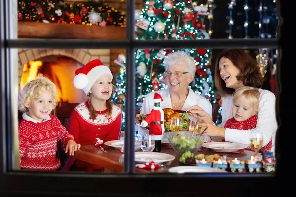 暖炉でクリスマスディナーを食べ クリスマスツリーを飾る子供たちと家族 両親や子供たちはお祝いの食事を楽しむ 冬の休日のお祝いや食べ物 祖母の料理ロースト七面鳥 — ストック写真