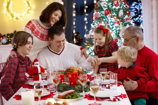 有孩子的家庭在壁炉边吃圣诞大餐 装饰着圣诞树 祖父母和孩子们正在享用节日大餐 寒假庆祝和食物 孩子们打开礼物和礼物 — 图库照片
