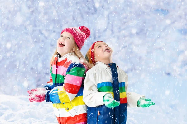 孩子们在雪地里玩耍 在下雪的冬天的一天 孩子在户外玩 男孩和女孩抓雪花在降雪风暴 弟弟和妹妹扔雪球 家庭圣诞假期活动 — 图库照片