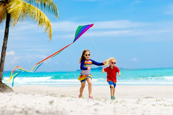 熱帯のビーチのカラフルな凧で実行の子 子供凧虹 小さな女の子がおもちゃの飛行機と海の海岸で遊んで エキゾチックな島の家族の夏休み 子供のための水と砂の楽しみ — ストック写真