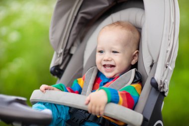 Sıcak renkli örgü ceket bir parkta bir yürüyüş modern bebek arabası oturan bebek çocuk. Çocuk arabası. Küçük çocuk bir olayından. Genç çocuklar seyahat. Bebek ile aile için ulaşım.