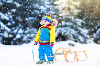 Küçük çocuk kızakla gezintiye çıkıyor. Çocuk kayağı. Kızak süren küçük bir çocuk. Çocuklar karda dışarıda oynarlar. Çocuklar kışın Alp dağlarında kızak kullanırdı. Aile Noel tatili için açık hava eğlencesi.