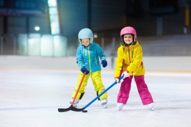 Çocuk kapalı pistinde buz hokeyi oyun. Çocuklar için sağlıklı kış sporları. Erkek ve kız hokey topu isabet sopa ile. Çocuk buz pateni. Spor okuldan sonra eğitim üzerinde küçük bir çocuk. Kar ve buz eğlenceli.