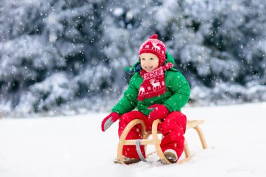 Küçük çocuk kızakla gezintiye çıkıyor. Çocuk kayağı. Kızak süren küçük bir çocuk. Çocuklar karda dışarıda oynarlar. Çocuklar kışın Alp dağlarında kızak kullanırdı. Aile Noel tatili için açık hava eğlencesi.
