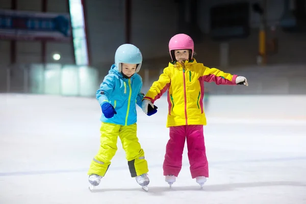 Children skating on indoor ice rink. Kids and family healthy winter sport. Boy and girl with ice skates. Active after school sports training for young child. Snow fun activity by cold weather.