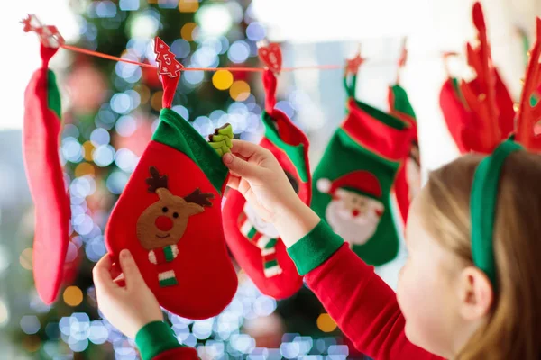 孩子们打开圣诞礼物 孩子在冬天的早晨寻找糖果和礼物在到来日历 装饰圣诞树为家庭与孩子 穿着圣诞睡衣的小女孩 — 图库照片