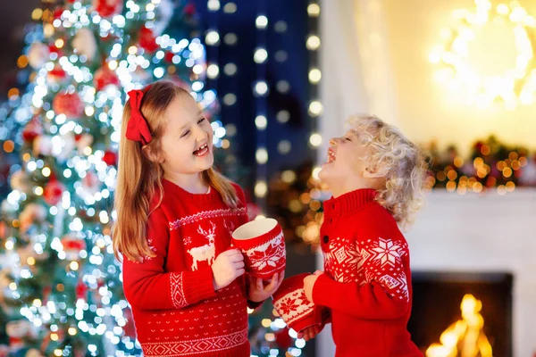 집에서 크리스마스 아이입니다 소년과 소녀와 크리스마스 스웨터에 초콜릿을 합니다 벽난로에서 — 스톡 사진