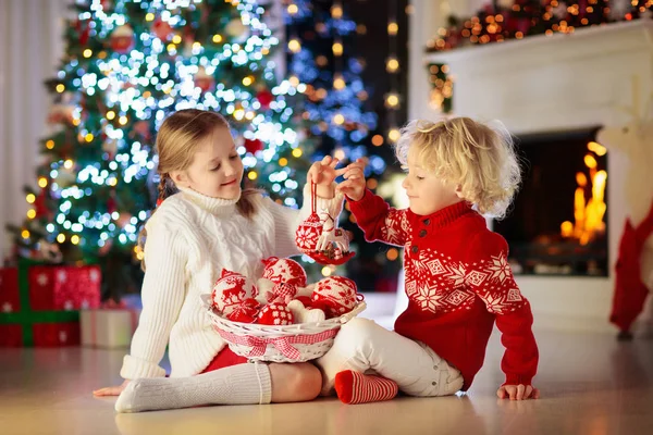 子供は自宅のクリスマス ツリーを飾るします 小さな男の子と女の子手作りのクリスマス飾り付きニット セーターに 冬の休日を祝っている家族 子供たちはクリスマスのためのリビング ルームと暖炉を飾る — ストック写真