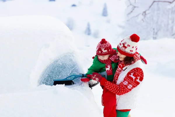 嵐の後 母親と子供のブラッシングや車をオフに雪をシャベル 一晩雪の吹雪の後 冬のブラシとスクレーパークリアファミリーカーと親子 山の中のクリスマス休暇 — ストック写真
