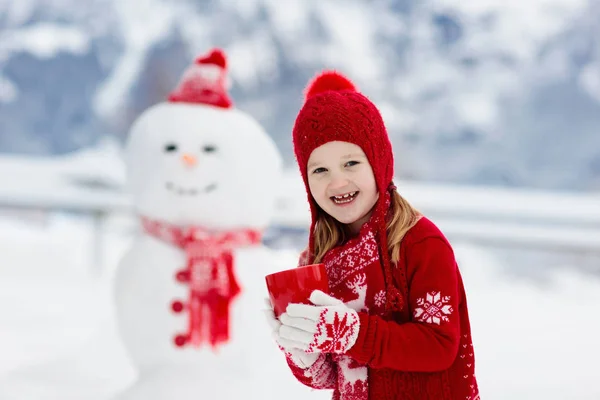 子供が雪だるまを作る 子供は雪男を作る 冬の雪の日に屋外で遊ぶ男の子と女の子 山の中でクリスマス休暇に屋外の家族の楽しみ 子供たちはスイスの山の風景で遊ぶ — ストック写真