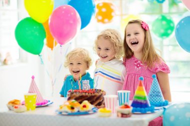 Doğum günü partisi çocuklar. Mum renkli kek üzerine dışarı üfleyen çocuk. Gökkuşağı bayrağı afiş, balonlar ile dekore edilmiş ev. Çiftlik hayvanları Tema kutlama. Küçük çocuk kutluyor Doğum günü. Parti gıda.