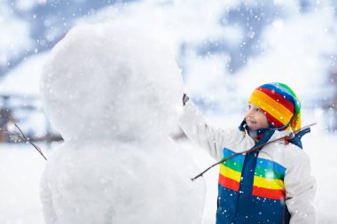 Çocuk bina kardan adam. Çocuklar kar adam inşa. Karlı kış günü açık havada oynama ufaklık. Noel tatil açık aile eğlencesi. Küçük çocuk oyun kar topları uçuş. Kış giyim etkin çocuk