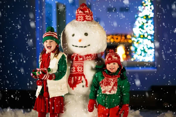 Kids Build Snowman Christmas Eve Children Snowy Backyard Next Window — Stock Photo, Image