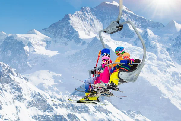 Family in ski lift in Swiss Alps mountains. Skiing with young kids. Father, mother and children sitting in ski lift during Christmas vacation. Winter outdoor sports for active family.