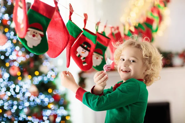 孩子们打开圣诞礼物 冬天早上 孩子们在日历上搜寻糖果和礼物 为有孩子的家庭装饰圣诞树 穿圣诞睡衣的小男孩 — 图库照片