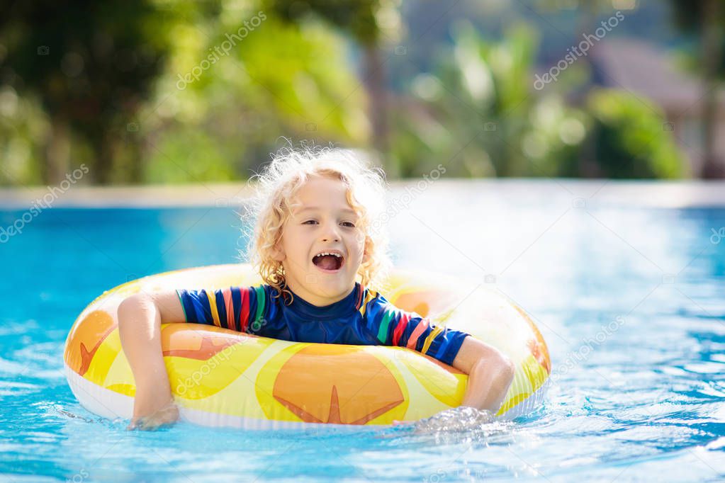Child with inflatable toy ring float in swimming pool. Little boy learning to swim and dive in outdoor pool of tropical resort. Swimming with kids. Healthy sport activity for children. Water fun.