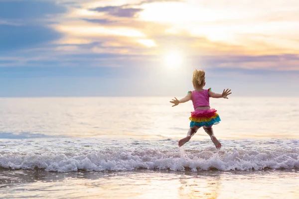 Criança brincando na praia do oceano. Miúdo ao pôr-do-sol . — Fotografia de Stock