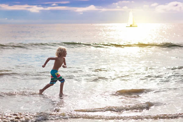 Bambino che gioca sulla spiaggia dell'oceano. Ragazzo al tramonto mare . — Foto Stock