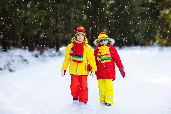 孩子们在雪地里玩耍 在下雪的冬天的一天 孩子在户外玩 男孩和女孩抓雪花在降雪风暴 弟弟和妹妹扔雪球 家庭圣诞假期活动 — 图库照片