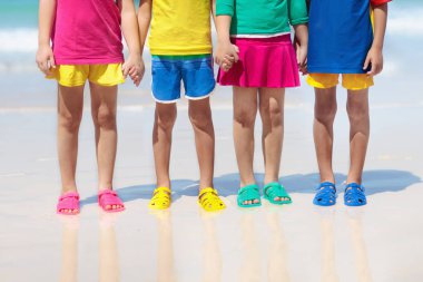 Çocuklar Ayakkabı plaj. Renkli ayakkabılar, erkek ya da kız için. Grup yaz tatile tropik sahilde oynarken aqua ayakkabı giyen çocuk. Su ve kum eğlenceli. Ayak ve bacaklar çocuklardan, kızlar. Güneşten korunma.