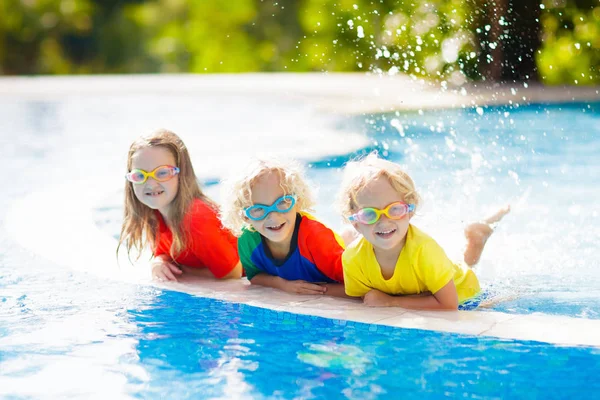 子供たちはプールで遊ぶ 子供家族夏休みトロピカル リゾートの屋外プールで泳ぐことを学ぶ 休日に若い子供のための水とスプラッシュの楽しい 子供や赤ちゃんの日焼け止め — ストック写真