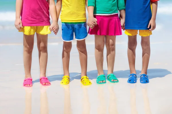 儿童沙滩鞋 男孩或女孩的五颜六色的鞋 暑假里 一群穿着水鞋在热带海滩玩耍的孩子们 水和沙子的乐趣 女孩的脚和腿 — 图库照片