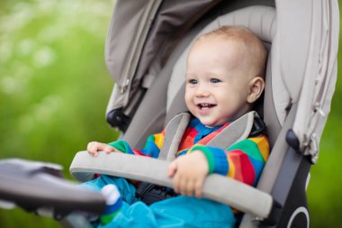 Sıcak renkli örgü ceket bir parkta bir yürüyüş modern bebek arabası oturan bebek çocuk. Çocuk arabası. Küçük çocuk bir olayından. Genç çocuklar seyahat. Bebek ile aile için ulaşım.