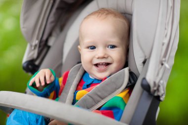 Sıcak renkli örgü ceket bir parkta bir yürüyüş modern bebek arabası oturan bebek çocuk. Çocuk arabası. Küçük çocuk bir olayından. Genç çocuklar seyahat. Bebek ile aile için ulaşım.