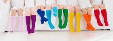 Renkli gökkuşağı çorapları giyen çocuklar. Çocuk ayakkabısı koleksiyonu. Diz boyu çorap ve tayt çeşitleri. Çocuk giysisi ve giysisi. Çocuk modası. Küçük erkek ve kız grubunun bacakları ve ayakları.