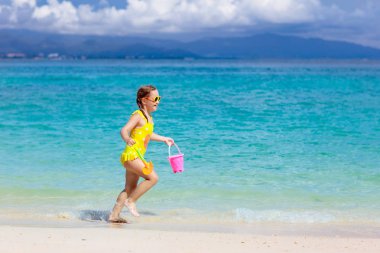 Tropik plajda oynayan bir çocuk. Deniz kıyısındaki küçük kız. Aile yaz tatili. Çocuklar su ve kum oyuncaklarıyla oynuyor. Okyanus ve ada eğlencesi. Küçük çocuklarla seyahat et. Asya tatili.