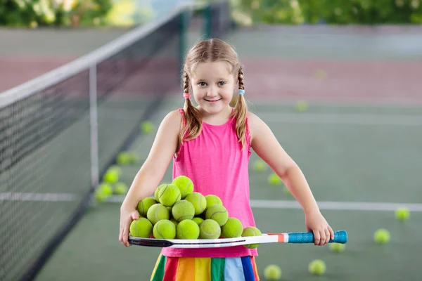 屋外コートでテニスの試合後のボール拾いの子 少女は スポーツ クラブでのトレーニングの後 ラケットとボールを収集します 子供のための健康的なスポーツ活動 子供の試合が終わった後のかたづけ — ストック写真