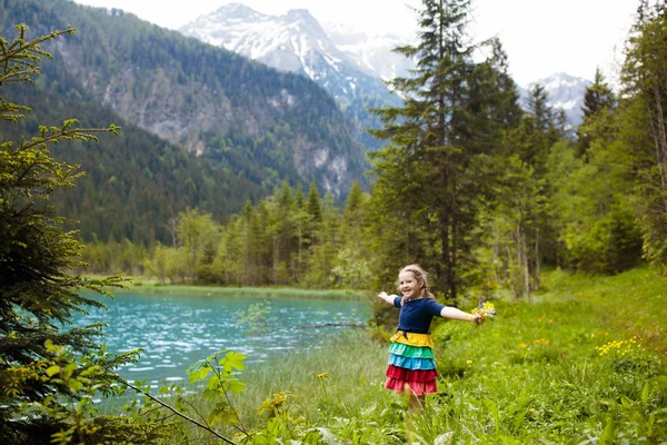 孩子徒步旅行在阿尔卑斯山看美丽的湖 孩子在高山花卉领域在雪被盖的山在奥地利 春天的家庭假期 小女孩在风景远足小径 户外娱乐 — 图库照片