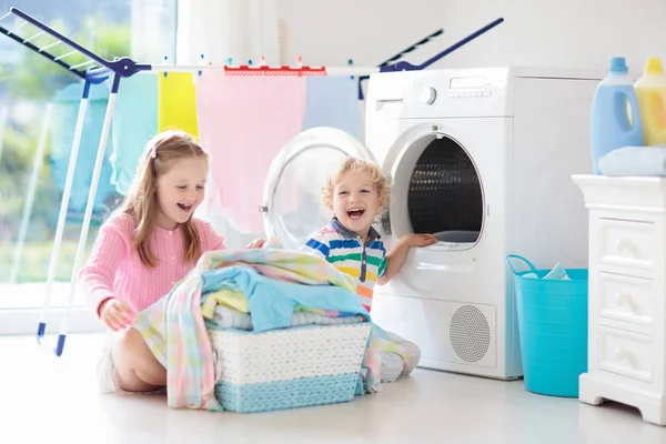 儿童在洗衣房内设有洗衣机或滚筒烘干机 孩子们帮助做家事 现代家庭设备和洗涤洗涤剂在白色阳光的家 烘干机架清洗洗衣服 — 图库照片