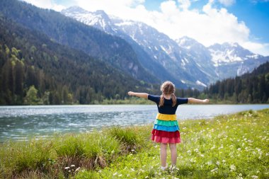 Çocuk güzel gölde seyir Alp Dağları'nda hiking. Karla kaplı dağ Avusturya alp çiçek alanında evlat. Bahar aile tatili. Küçük kız doğal zammı izinde. Açık eğlence.