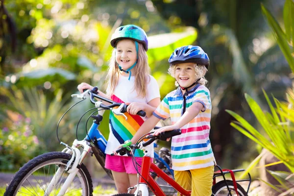 公園で自転車に乗っている子供たち 子供たちは安全な自転車のヘルメットを着て学校に行く 晴れた夏の日に男の子と女の子の自転車 若い子供のためのアクティブな健康的な屋外スポーツ 子供のための楽しい活動 — ストック写真