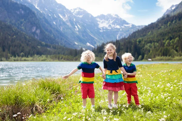 孩子们在阿尔卑斯山上徒步旅行 看着美丽的湖泊 孩子在高山花卉领域在雪盖的山在奥地利 春天的家庭假期 女孩和男孩在徒步旅行路线 户外娱乐 — 图库照片